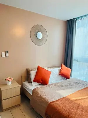 a bedroom with a bed with orange pillows and a window at BGC Simple Elegant 300Mbps Wifi,Pool,Netflix in Manila