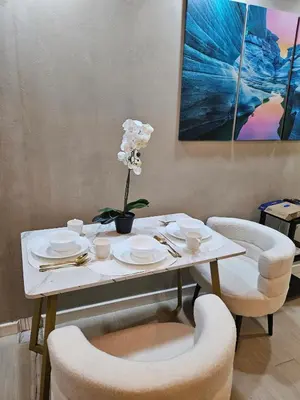 a white table with chairs and a white flower on it at Cozy Apartment Azure Urban Resort Residences in Manila