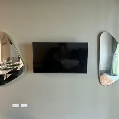 a flat screen tv on a wall with two mirrors at King Size 3-Bedroom in Uptown Parksuites BGC in Manila