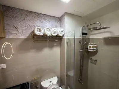 a bathroom with a shower and a toilet and towels at Casa y' Bonita MOA Pasay Staycation in Manila