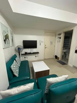 a living room with two green chairs and a tv at Azure Condo Maui by arlene in Manila