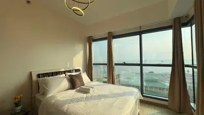 a bedroom with a bed and a large window at 2BR Grand Riviera Suites by MrSayla in Manila