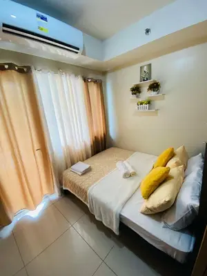 a bedroom with a bed with yellow pillows on it at Pool view 333d near moa with balcony in Manila