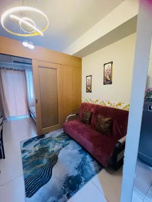a living room with a red couch and a rug at Pool view 333d near moa with balcony in Manila