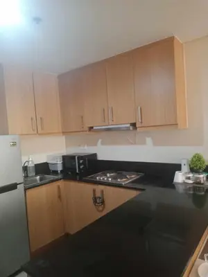 a kitchen with wooden cabinets and a black counter top at 2bedroom with big balcony 1046D pool view in Manila