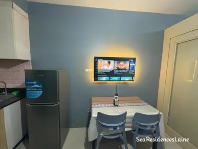 a kitchen with a table and a tv on the wall at Sea Residences by Laine in Manila