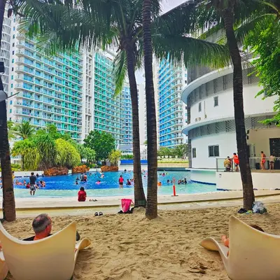 a man sitting in chairs on the beach at a resort at Azure Urban Resort Residences by Moldez Staycation in Manila