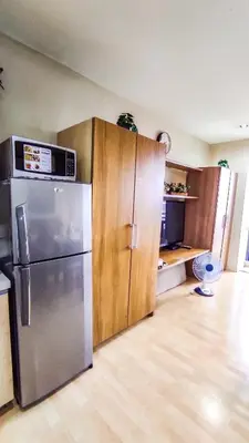 a kitchen with a stainless steel refrigerator and wooden cabinets at Cozy Apartment City & Mountain View with balcony FREE use of pools sauna and sunbathing in Manila