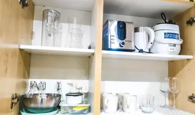 a kitchen cabinet filled with lots of kitchen items at Cozy Apartment City & Mountain View with balcony FREE use of pools sauna and sunbathing in Manila