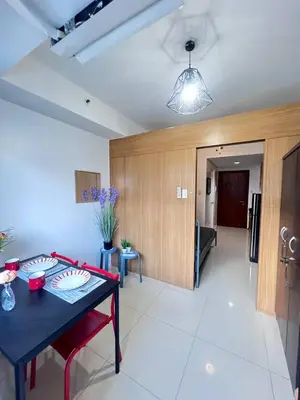 a living room with a table and a dining room at Unistay SHELL Residences Amazing Pool view near MOA in Manila