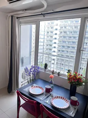 a dining room table with plates on it in front of a window at Unistay SHELL Residences Amazing Pool view near MOA in Manila