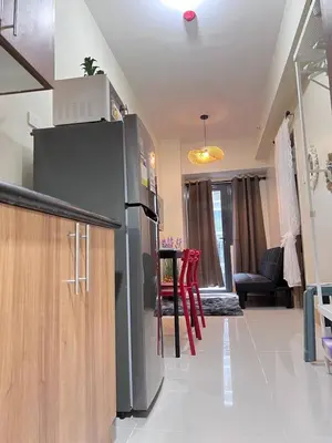 a kitchen with a refrigerator and a table in a room at Unistay SHORE 3 Tower 2 Pool View Cozy Suite in Manila