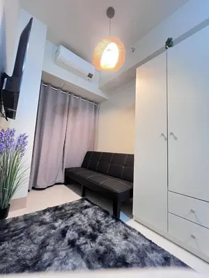 a living room with a black couch and a white cabinet at Unistay SHORE 3 Pool view w Balcony near MOA in Manila