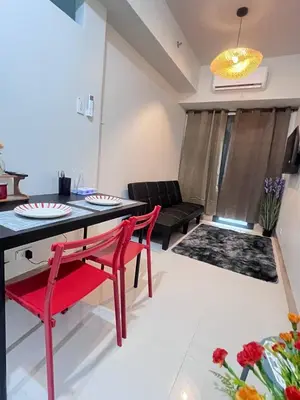a living room with a table and chairs and a couch at Unistay SHORE 3 Tower 2 10th Floor w Balcony Pool View in Manila