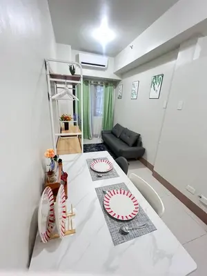 a living room with a table with plates on it at Unistay SHORE 3 Poolview w Balcony in Manila