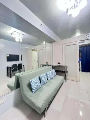 a living room with a green couch with two pillows at Sojourn at Sea Residences MOA in Manila