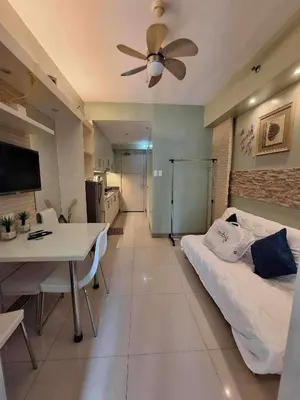 a bedroom with a bed and a table and a ceiling fan at Sojourn at Sea Residences MOA in Manila
