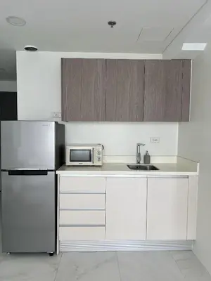 a kitchen with white cabinets and a stainless steel refrigerator at Cloud Space Studio near Eastwood in Manila