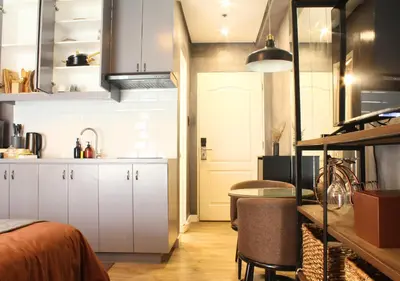 a kitchen with white cabinets and a table in a room at The Brass Burrow, Bel Air Soho Suites in Manila