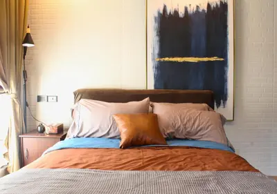 a bedroom with a bed with a painting on the wall at The Brass Burrow, Bel Air Soho Suites in Manila