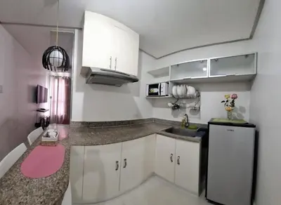 a small kitchen with white cabinets and a pink sink at Modern Studio Birch Tower Near Malls & Nightlife in Manila