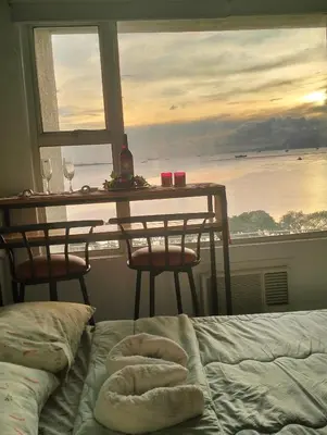 a bedroom with a bed and a table with a view of the ocean at Chic Haven in Manila