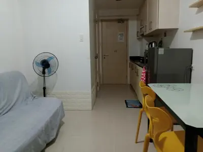 a kitchen with a table and a fan in a room at Sea Residence Finest By Douie in Manila