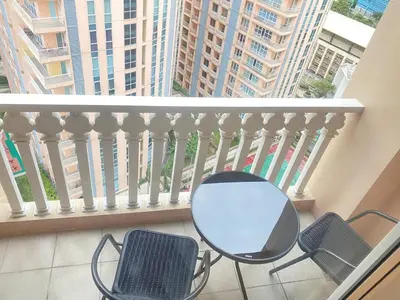 a table and chairs on a balcony with a view of a building at The Serene Casa - EMANUELE TOWER in Manila