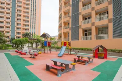 a playground with benches and a slide in front of a building at The Serene Casa - EMANUELE TOWER in Manila