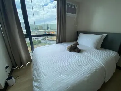 a teddy bear sitting on a bed in front of a window at 2mins to Okada near Airport & MOA with Balcony-8E in Manila