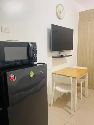a kitchen with a refrigerator and a table with a tv at Shore 1 Condo near MOA - PLS send valid IDs of all guests after booking for guest authorization form purposes in Manila