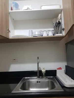 a kitchen sink with cups and dishes on a shelf at Shore 2 Residences MOA Pasay Naia in Manila