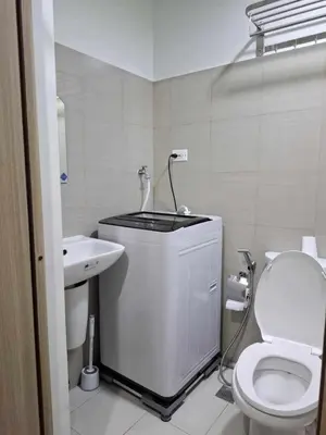 a white bathroom with a toilet and a sink at Shore 2 Residences MOA Pasay Naia in Manila