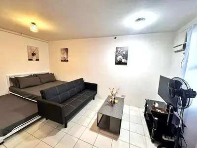 a living room with a black couch and a television at Luna staycation Cozy Condo near Enchanted Kingdom in Santa Rosa