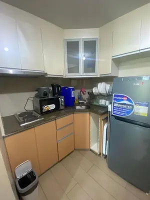 a small kitchen with white cabinets and a refrigerator at two palm tree villas condotel by kath in Manila