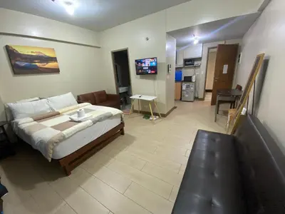 a bedroom with a bed and a living room at two palm tree villas condotel by kath in Manila