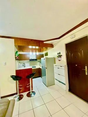 a kitchen with a refrigerator and two bar stools at Dym cozy condo pad in Manila