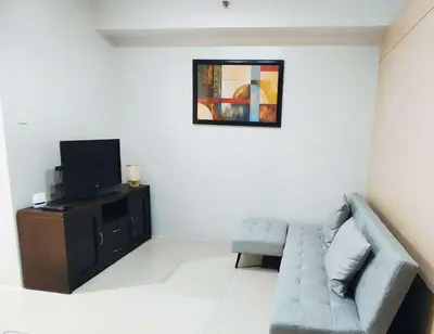a living room with a couch and a tv at Suite Escapade in Manila