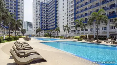 a large swimming pool with lounge chairs and buildings at Suite Escapade in Manila