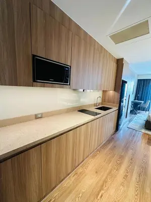 a kitchen with wooden cabinets and a counter top at MADR Excellence at Novotel Manila Hotel Residence Acqua in Manila