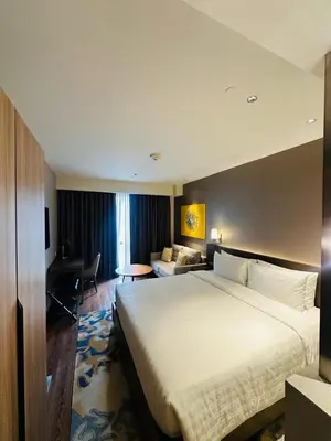 a hotel room with a large bed and a desk at MADR Excellence at Novotel Manila Hotel Residence Acqua in Manila
