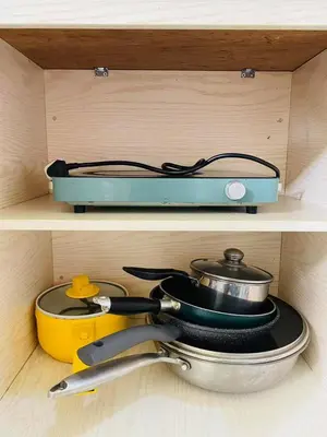 a shelf with a pot and pans in a drawer at timoncondotel city view in Manila