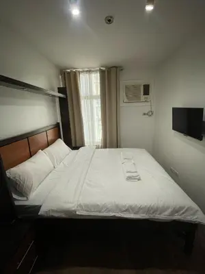 a bedroom with a large bed with white sheets at The Serenity Tower 2610 in Manila