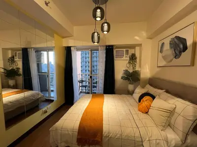 a bedroom with a large bed and a window at CASA ROYALE Affordable Condo Near BGC Ortigas Center CBD in Manila
