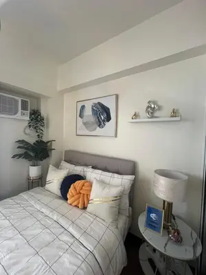 a bedroom with a bed with an orange pillow on it at CASA ROYALE Affordable Condo Near BGC Ortigas Center CBD in Manila