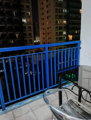 a table and a chair on a balcony at night at Bj's Staycation Manila - SEA Residences SM MOA in Manila