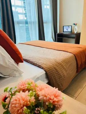 two beds in a hotel room with flowers on a table at BGC One Uptown Residences in Manila