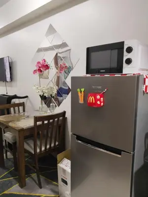a refrigerator with a microwave on top of it next to a table at The Chill Spot Residences Property Management in Manila
