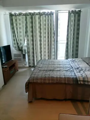 a bedroom with a bed and a tv and curtains at Premium 1Bedroom Condo Unit Near Airport, MOA, Casinos, SM Bicutan in Manila