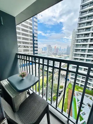 a balcony with a table and a chair and a view of a city at Serenitude Staycation by Khaila - Fame Residences in Manila